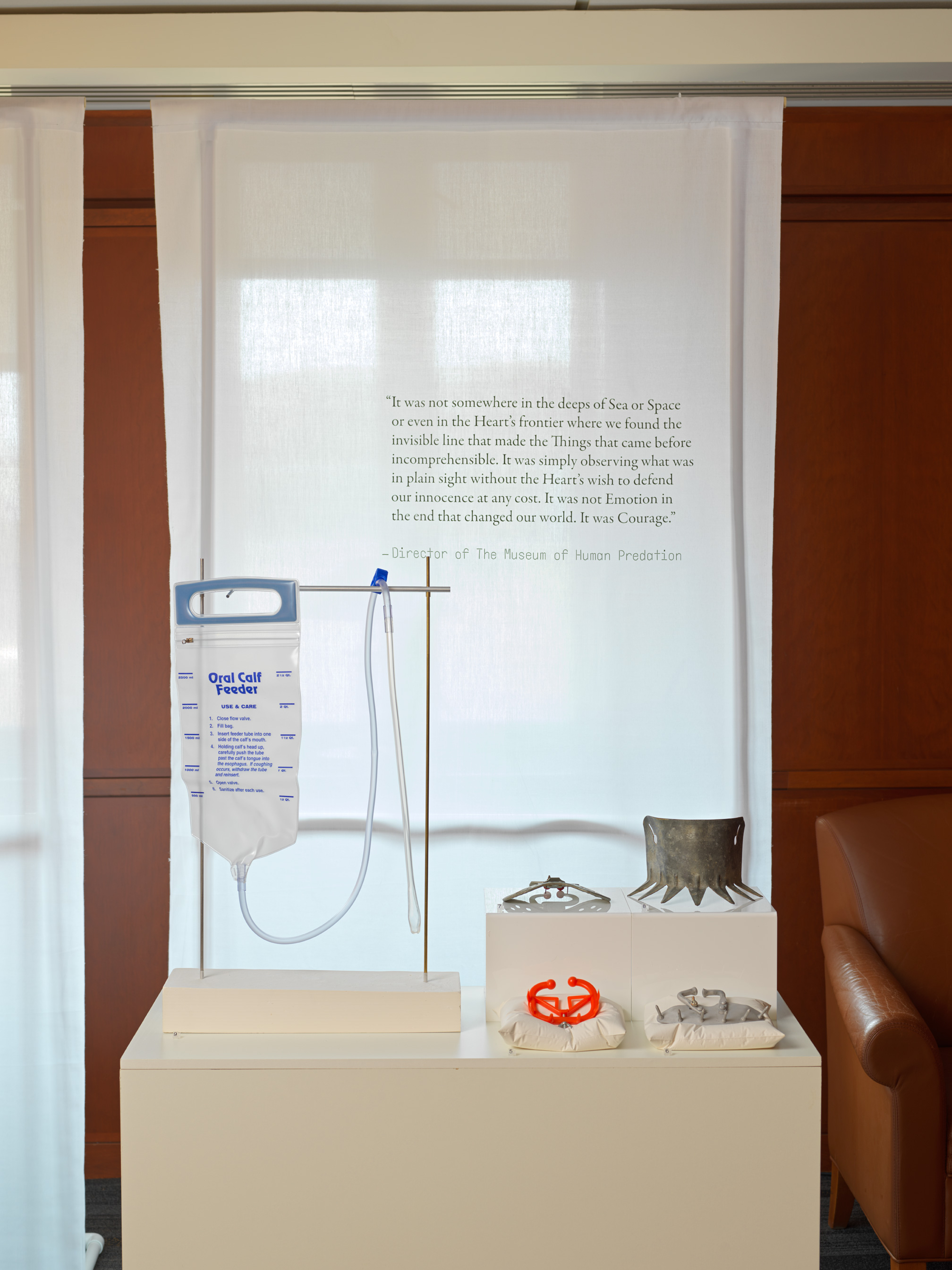 Display of an esophageal calf feeder and anti-suckling devices with a banner behind it