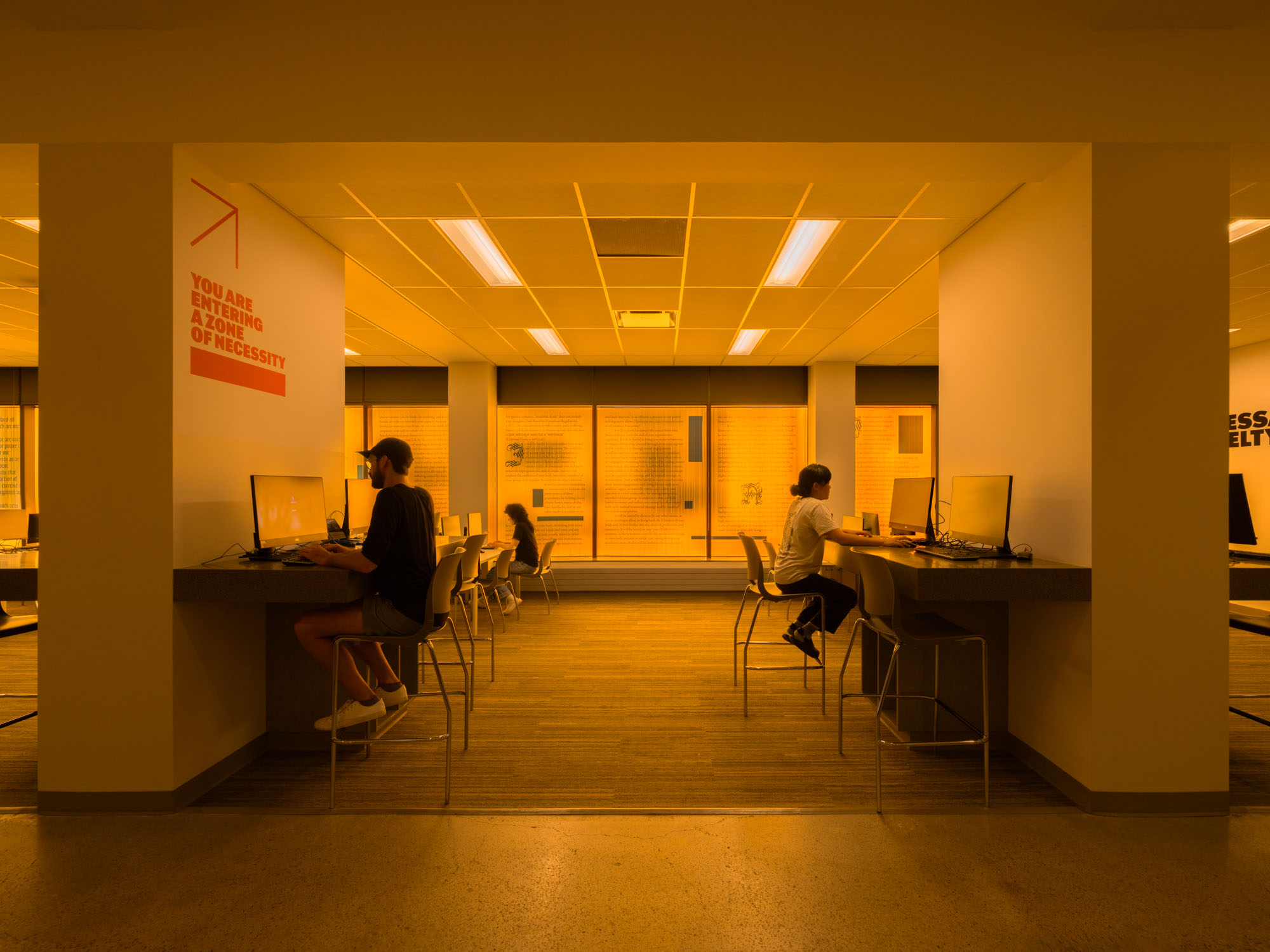 Students at computers at the Bora Laskin Law Library information commons during the Necessary Cruelty exhibition.