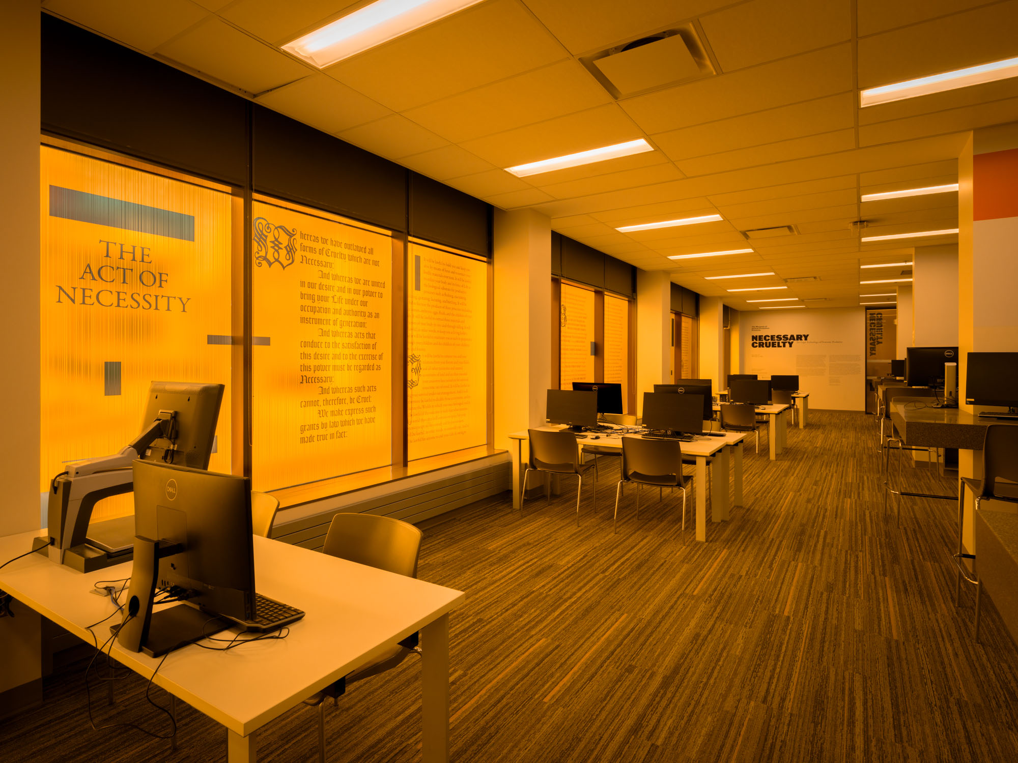 The Act of Necessity text window vinyl casting an orange hue in the Bora Laskin Law Library information commons.